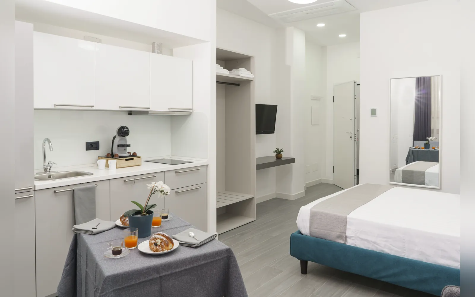 L’angolo cottura bianco con il tavolo e, sullo sfondo, il letto