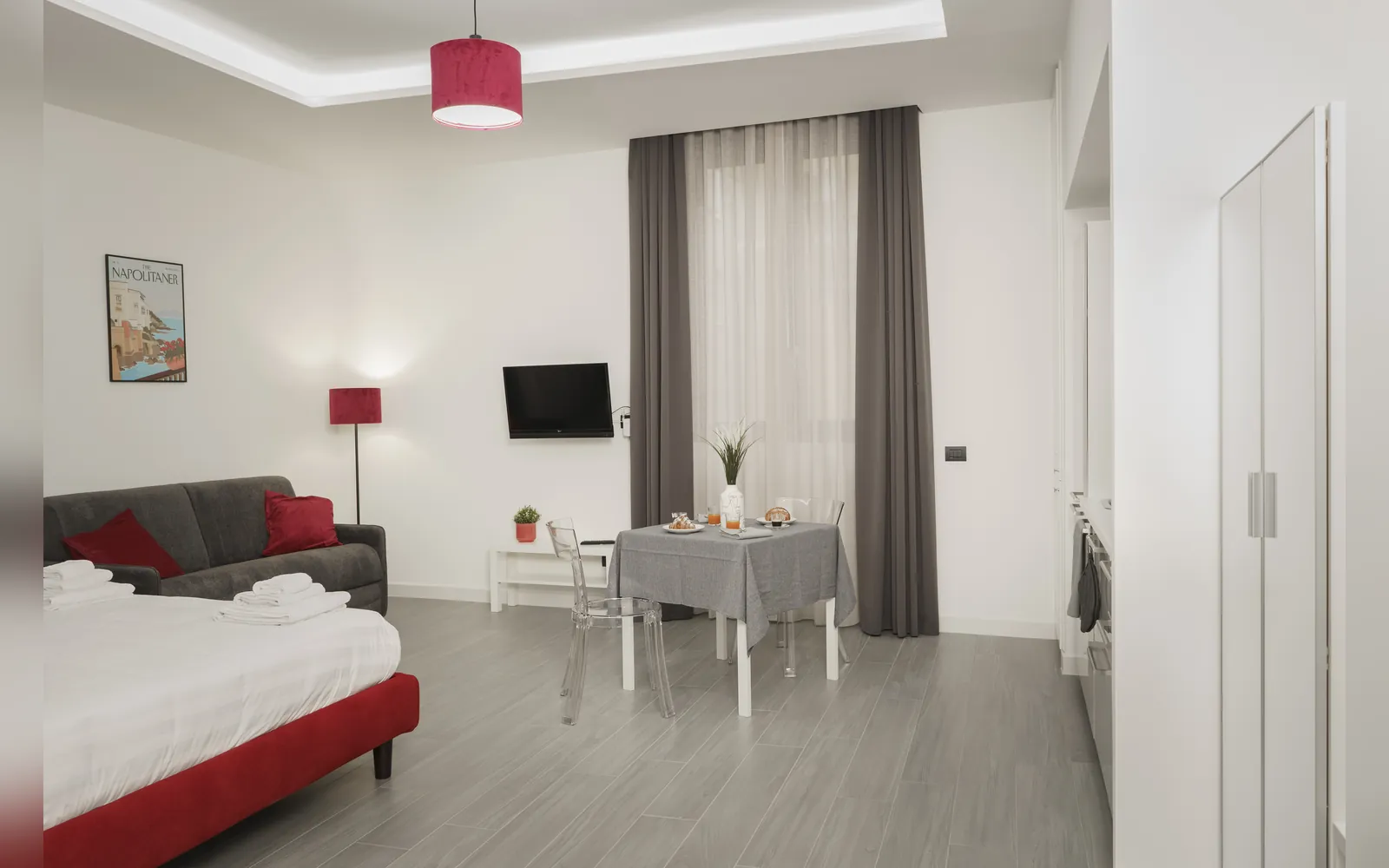 Il monolocale dall’ingresso: letto rosso, divano e tavolo
