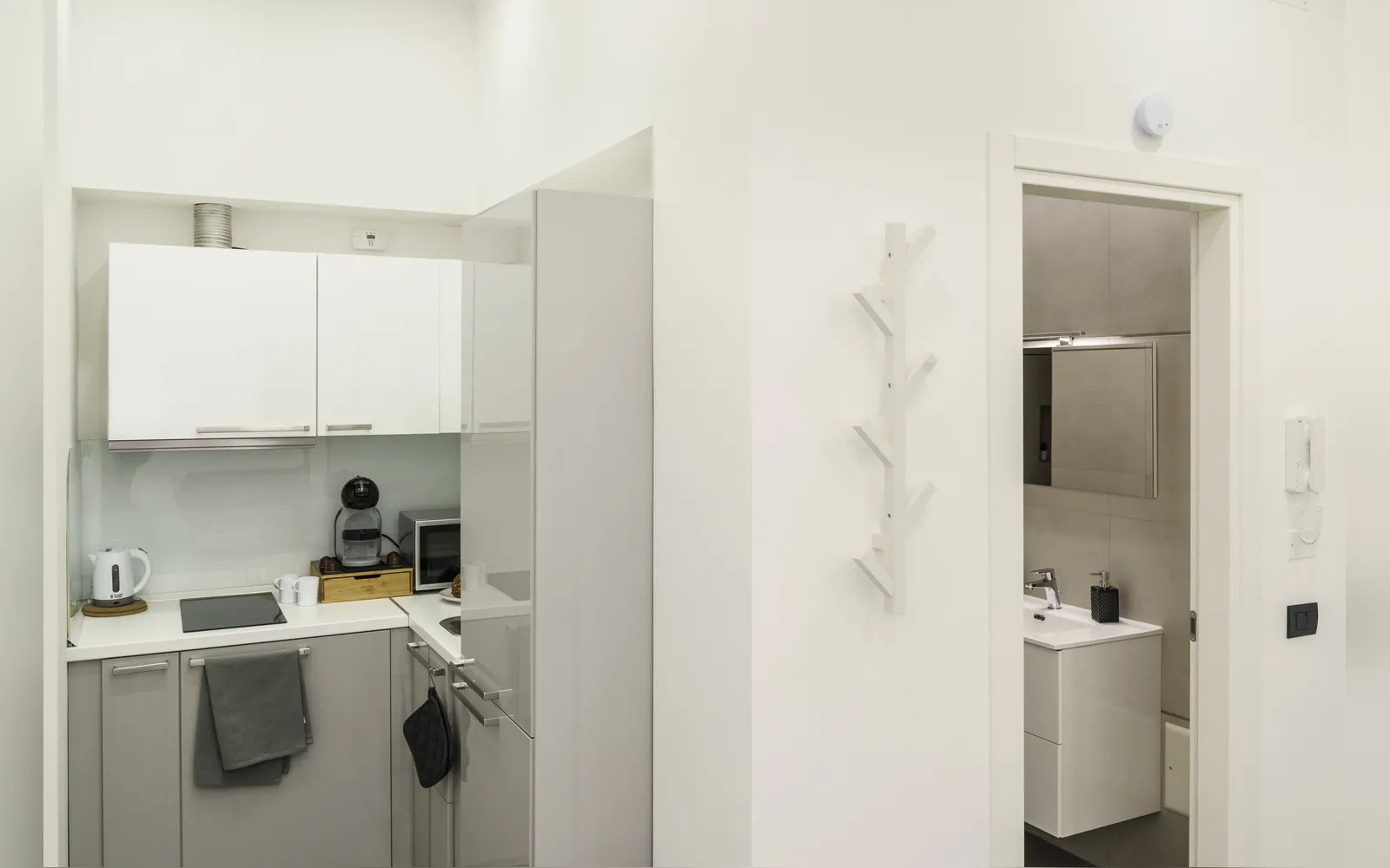 L’angolo cottura bianco e la porta del bagno